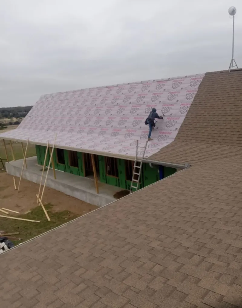 Worker preparing underlayment for a metal roof installation in Hermiston